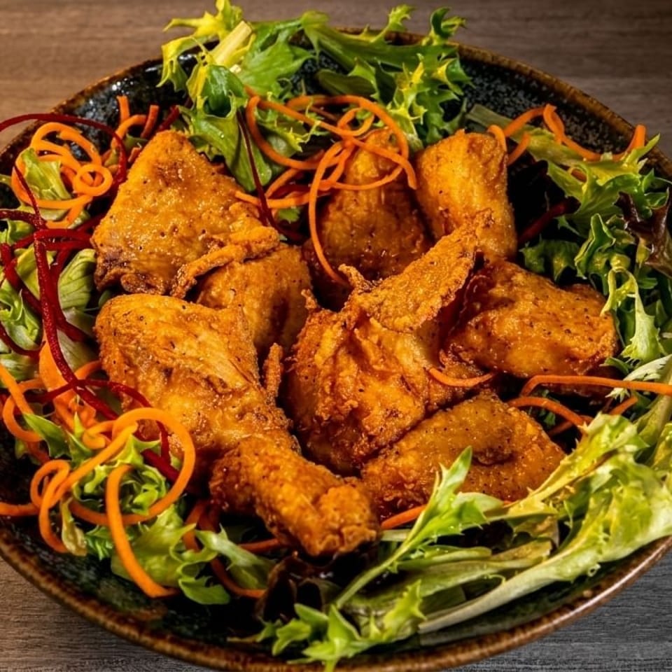 Crispy fried chicken pieces served on a bed of fresh green salad with shredded carrots and red beet.