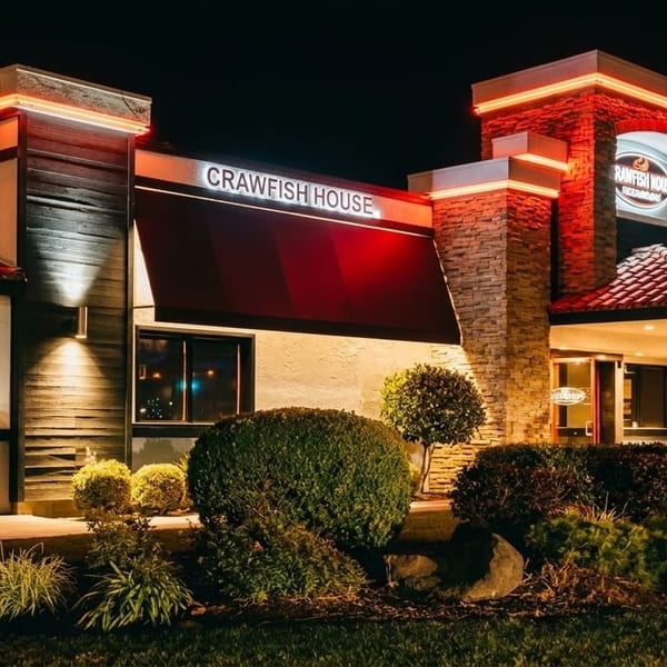 Exterior of Crawfish House restaurant at night, with red neon signs and illuminated landscaping.
