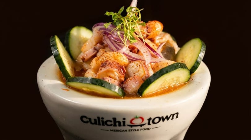 Culichitown Mexican-style food: a white bowl filled with ceviche, garnished with cucumber, red onion, and cilantro.