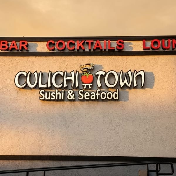Exterior sign for "CuliChi Town Sushi & Seafood Bar Cocktails Lounge" with a tomato and shrimp logo.